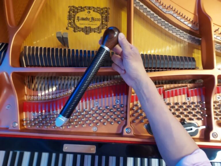 Technicien examinant les cordes et le cadre d’un piano à queue