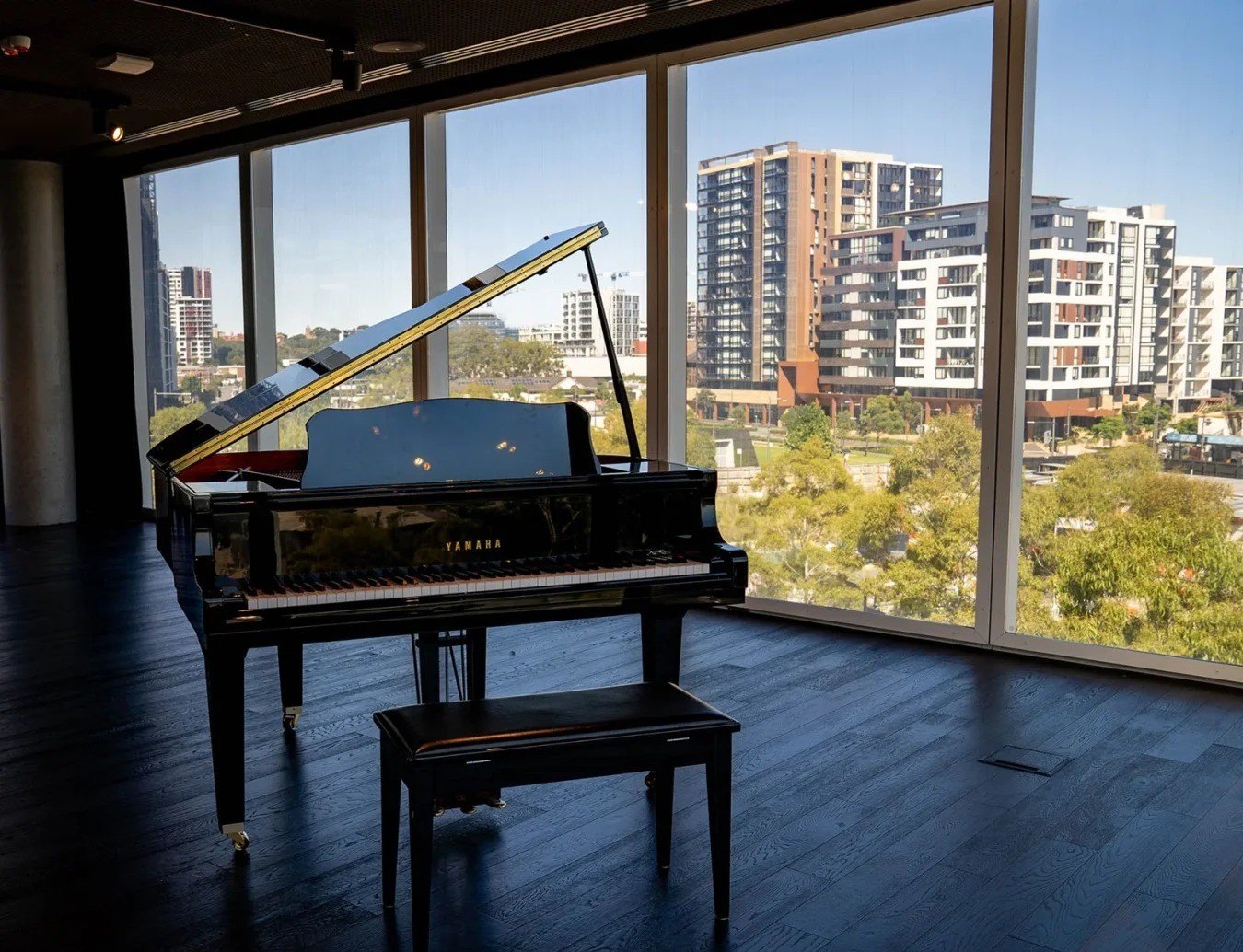 Piano à queue devant une baie vitrée en ville